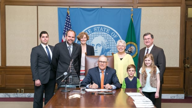 Washington Gov. Jay Inslee (seated, center) signed legislation that could attract more superyacht visitors to the state.