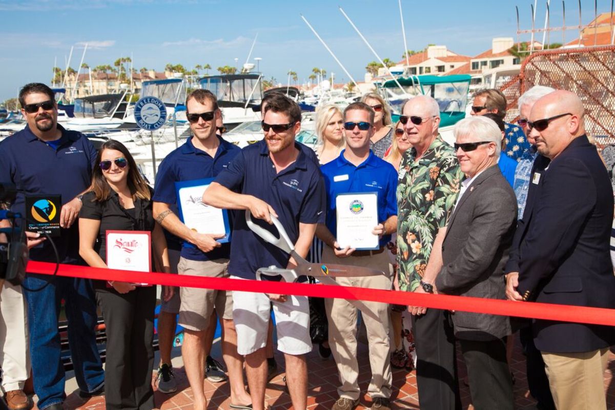 Andrew Hard, owner-operator of the Freedom Boat Club franchise in Huntington Beach, Calif., cuts the ribbon during grand opening festivities. Hard is flanked by Freedom Boat Club President and CEO John Giglio (right) and San Diego franchise owners Dan Hasbrouck and his wife, Jennifer (left), along with a group of regional dignitaries and VIPs.