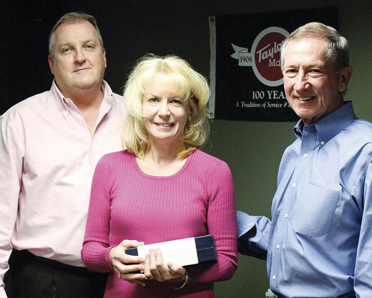 Gayle Maye, director of customer service for Taylor Made Systems, is shown receiving an award in 2014 for her outstanding commitment to the company from Allan Petit (left), president of Taylor Made Systems, and Dennis Flint, chairman and CEO of The Taylor Made Group.