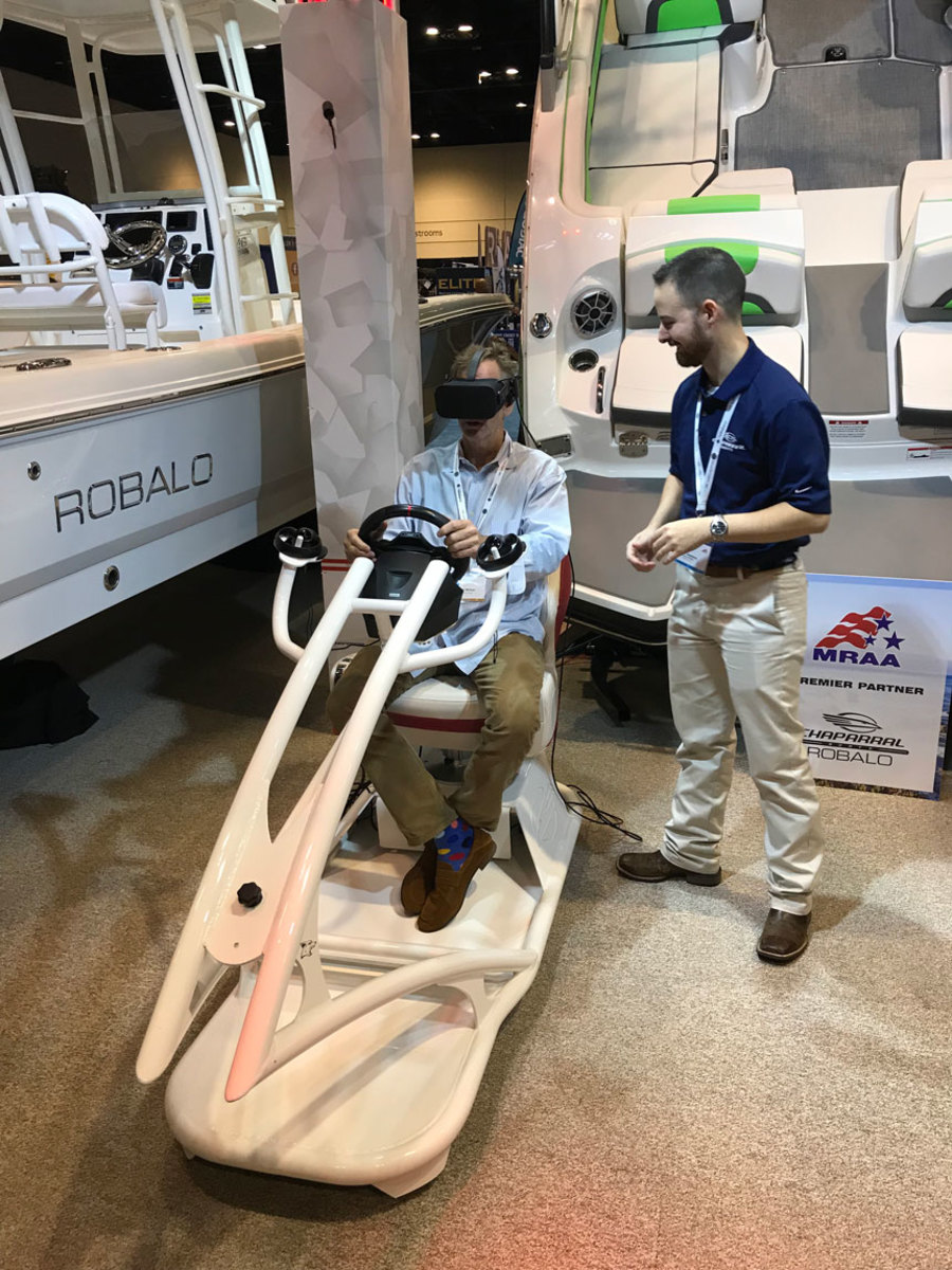 An MDCE conferee tries out the virtual-reality system built by Ryan Swaims (right), website creative director for Chaparral and Robalo Boats. The system allowed MDCE visitors to “test-drive” the latest boats.