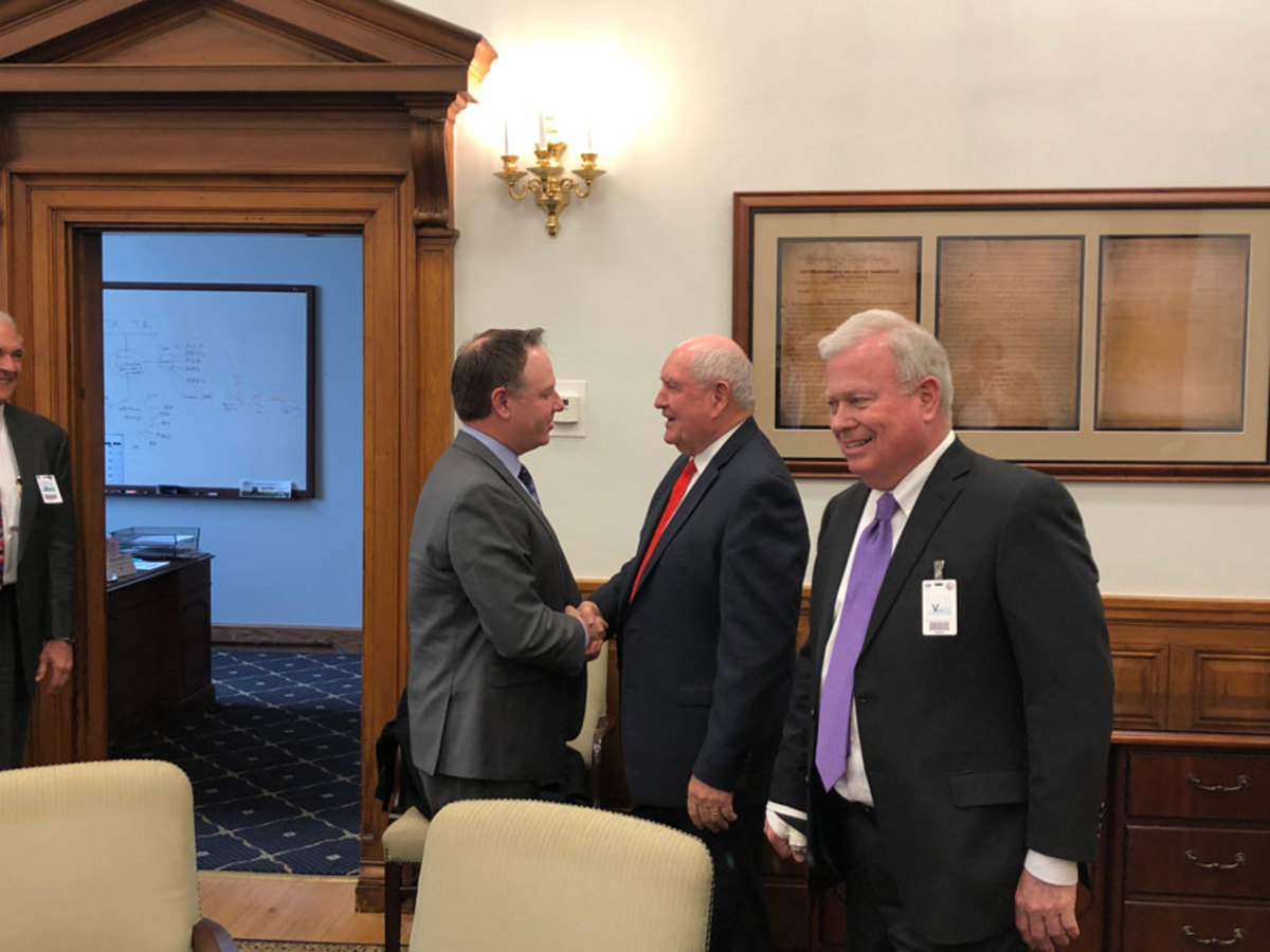 Winnebago CEO Mike Happe shaking hands with UDA Secretary Sonny Perdue. Thom Dammrich, NMMA president and ORR chairman, is in the foreground.