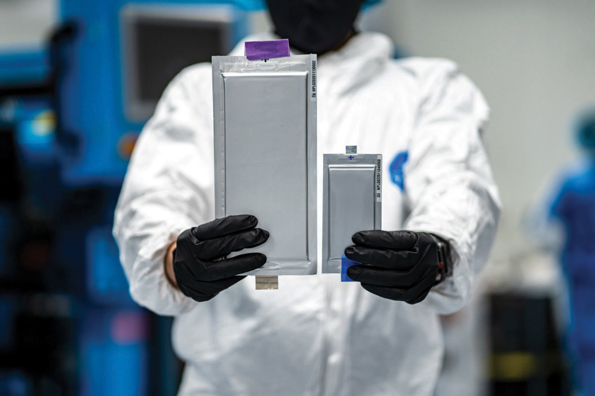 A Solid Power engineer shows its new (left) 22-layer, solid-state lithium 